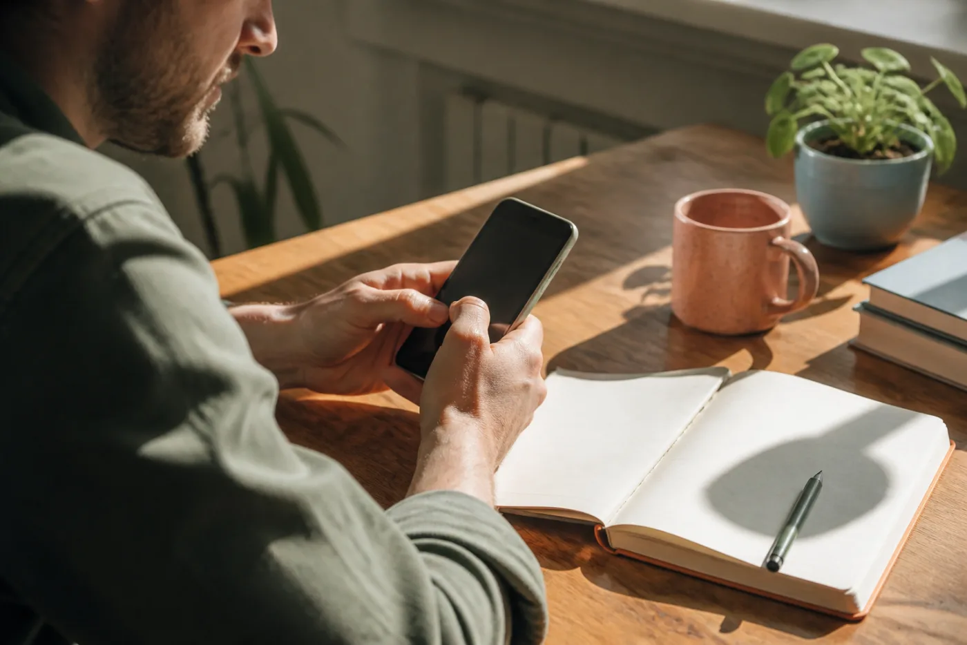 A neurodivergent adult at a sunlit desk, pausing while writing a message to someone they are dating.